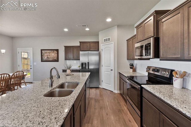 11052 Bossett Dr, Peyton, CO 80831 - kitchen with appliances with stainless steel finishes, a sink, light wood-style flooring, recessed lighting, and light stone countertops