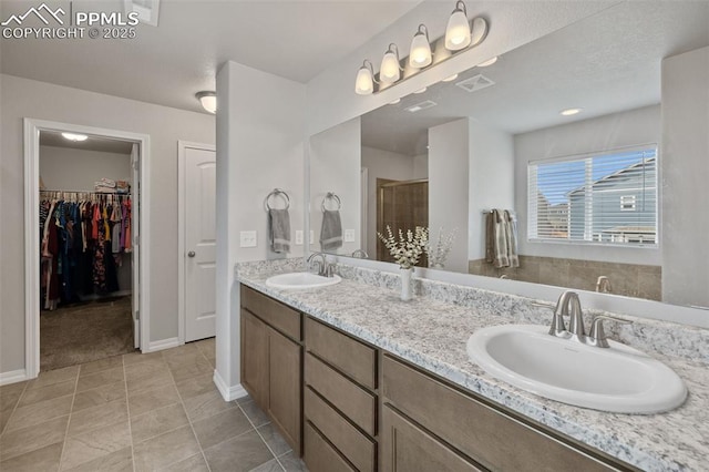 11052 Bossett Dr, Peyton, CO 80831 - bathroom with double vanity, a stall shower, baseboards, a walk in closet, and tile patterned flooring