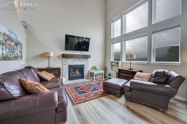 6927 Passing Sky Dr, Colorado Springs, CO 80911 - living room with wood finished floors, a towering ceiling, and a stone fireplace