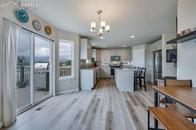 6927 Passing Sky Dr, Colorado Springs, CO 80911 - kitchen with appliances with stainless steel finishes, a chandelier, light wood finished floors, a center island, and recessed lighting