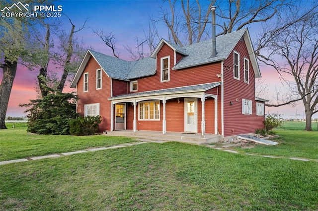 view of front of property featuring covered porch, a front lawn, and roof with shingles