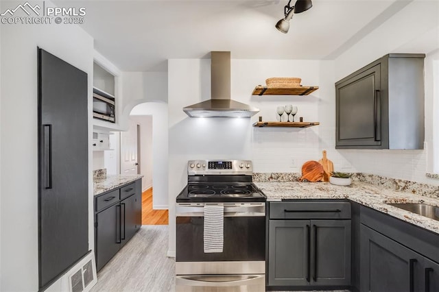 5362 S Cedar St, Littleton, CO 80120 - kitchen featuring appliances with stainless steel finishes, wall chimney range hood, arched walkways, decorative backsplash, and light wood finished floors