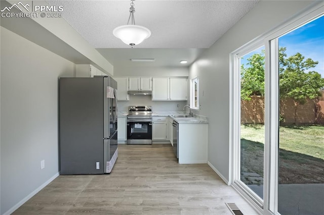 502 Fountain Mesa Rd, Fountain, CO 80817 - kitchen with stainless steel appliances, a sink, under cabinet range hood, light countertops, and white cabinetry