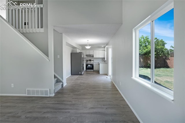 502 Fountain Mesa Rd, Fountain, CO 80817 - hall featuring stairway, dark wood finished floors, healthy amount of natural light, and baseboards