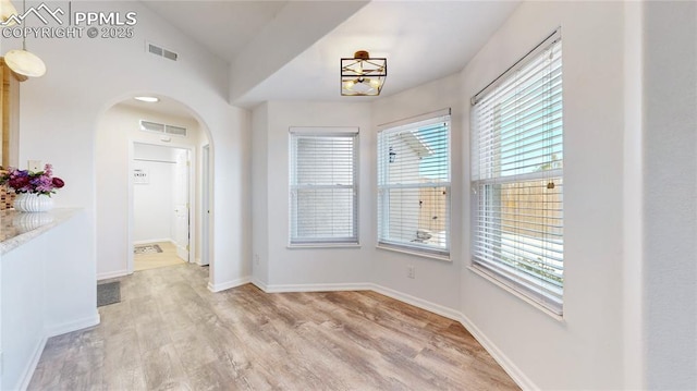 14870 Reiner Ct, Peyton, CO 80831 - unfurnished dining area with plenty of natural light, light wood finished floors, arched walkways, baseboards, and vaulted ceiling