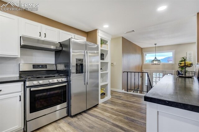 3905 Allgood Dr, Colorado Springs, CO 80911 - kitchen with under cabinet range hood, stainless steel appliances, white cabinets, dark countertops, and light wood finished floors