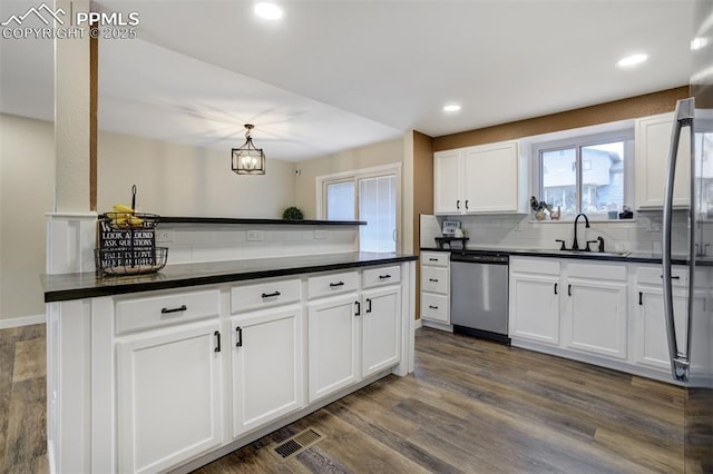 3905 Allgood Dr, Colorado Springs, CO 80911 - kitchen with stainless steel dishwasher, a sink, dark countertops, decorative backsplash, and white cabinetry