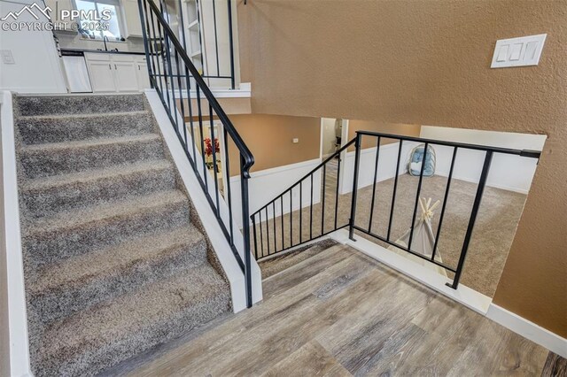 3905 Allgood Dr, Colorado Springs, CO 80911 - staircase featuring wood finished floors, baseboards, and a textured wall