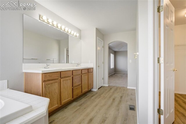 1264 Castle Hills Pl, Colorado Springs, CO 80921 - bathroom with wood finished floors, double vanity, baseboards, and a bath