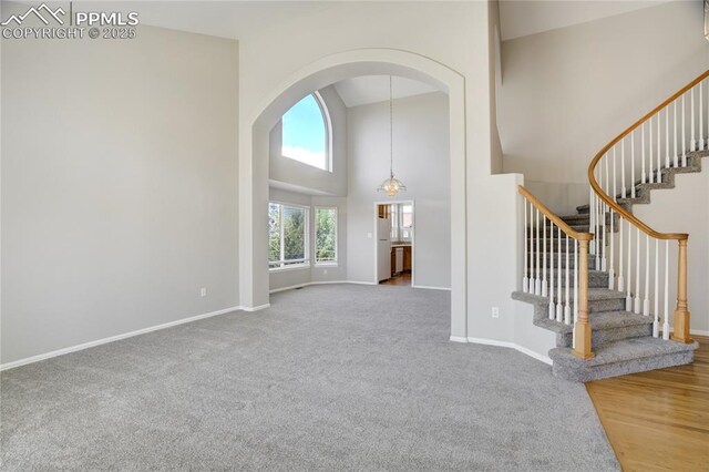 1264 Castle Hills Pl, Colorado Springs, CO 80921 - entryway featuring high vaulted ceiling, baseboards, carpet floors, arched walkways, and stairs