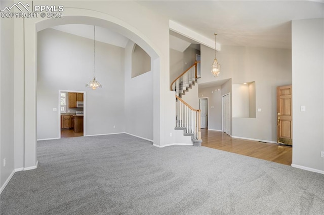 1264 Castle Hills Pl, Colorado Springs, CO 80921 - unfurnished living room with carpet floors, high vaulted ceiling, stairway, baseboards, and a chandelier