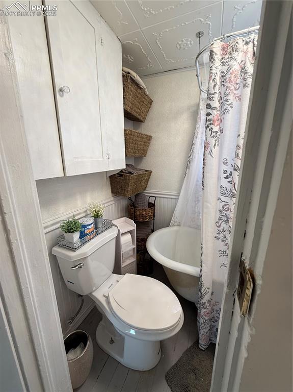 2932 W Kiowa St, Colorado Springs, CO 80904 - bathroom with toilet, wainscoting, and a shower with shower curtain