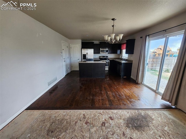 6282 Pilgrimage Rd, Colorado Springs, CO 80925 - kitchen with appliances with stainless steel finishes, a chandelier, a sink, dark cabinets, and a kitchen island