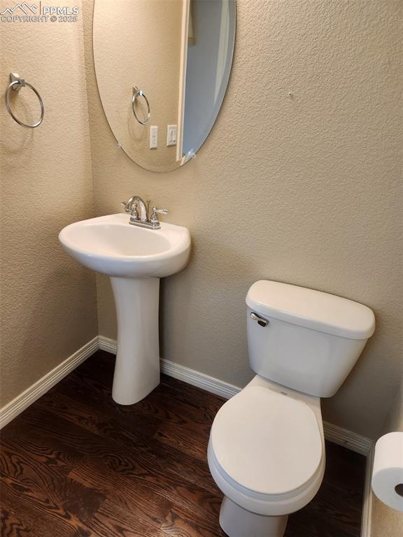 6282 Pilgrimage Rd, Colorado Springs, CO 80925 - bathroom with wood finished floors, toilet, baseboards, and a sink