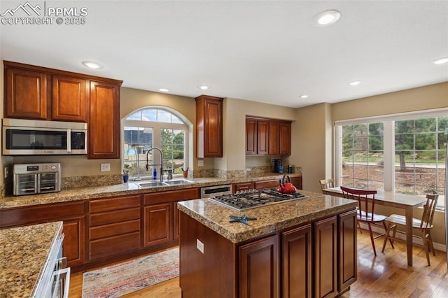kitchen featuring stainless steel appliances, a sink, light wood-type flooring, recessed lighting, and a kitchen island