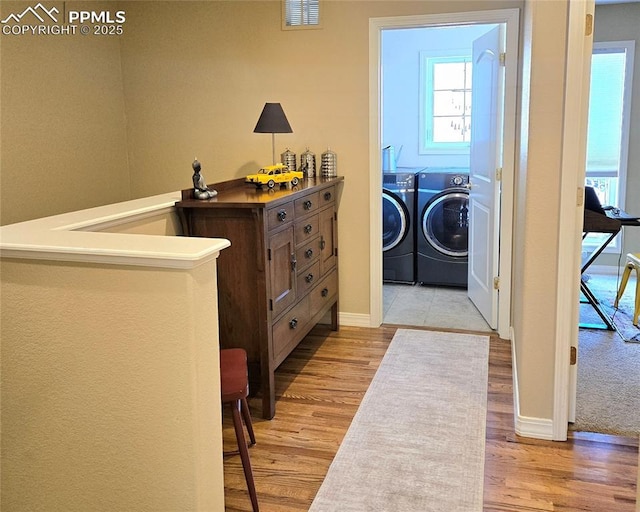 laundry room with washer and clothes dryer, light wood-type flooring, and baseboards