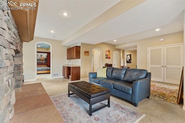 living area featuring arched walkways, light carpet, recessed lighting, and baseboards