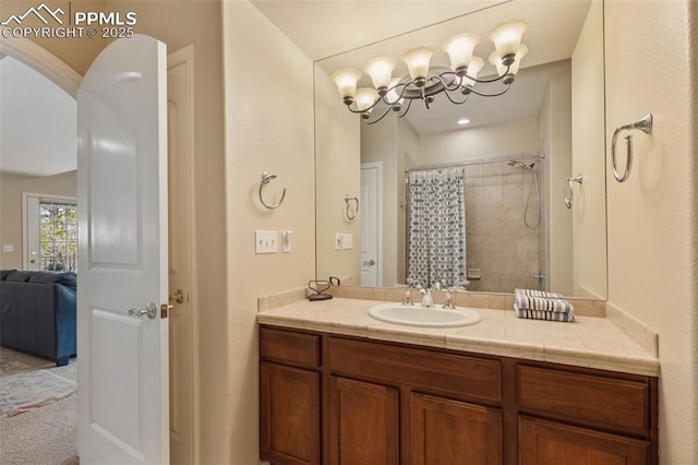 bathroom with vanity, a chandelier, a tile shower, and ensuite bath