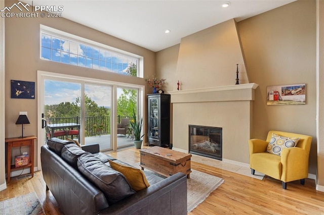 living room with light wood finished floors, baseboards, a high ceiling, a fireplace, and recessed lighting
