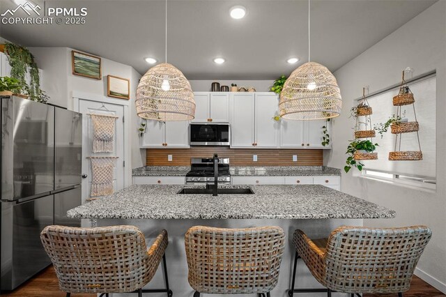7907 Tremble Pt, Colorado Springs, CO 80908 - kitchen featuring appliances with stainless steel finishes, a sink, backsplash, white cabinets, and dark wood-type flooring