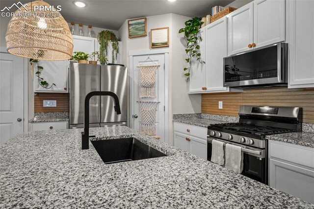 7907 Tremble Pt, Colorado Springs, CO 80908 - kitchen with appliances with stainless steel finishes, a sink, white cabinetry, light stone counters, and recessed lighting