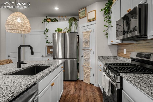 7907 Tremble Pt, Colorado Springs, CO 80908 - kitchen with stainless steel appliances, a sink, decorative backsplash, hanging light fixtures, and white cabinets