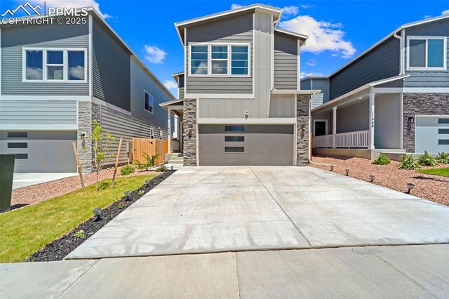11456 Sanderling St, Colorado Springs, CO 80925 - contemporary house featuring stone siding, an attached garage, driveway, board and batten siding, and covered porch