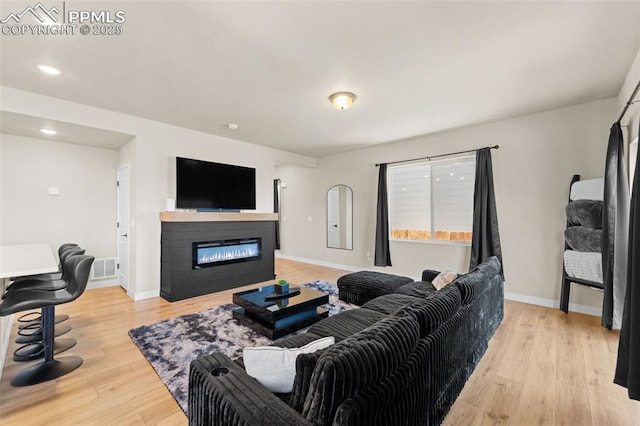 11456 Sanderling St, Colorado Springs, CO 80925 - living room with light wood-type flooring, a glass covered fireplace, baseboards, and recessed lighting
