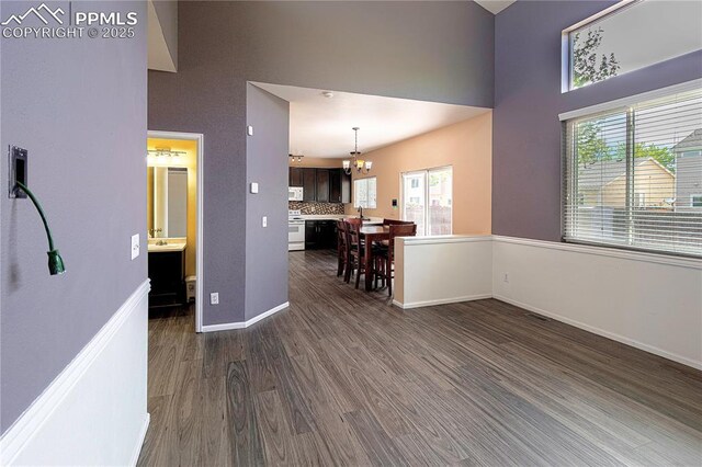 3808 Happy Jack Dr, Colorado Springs, CO 80922 - empty room featuring dark wood-style floors, a chandelier, a high ceiling, baseboards, and a sink