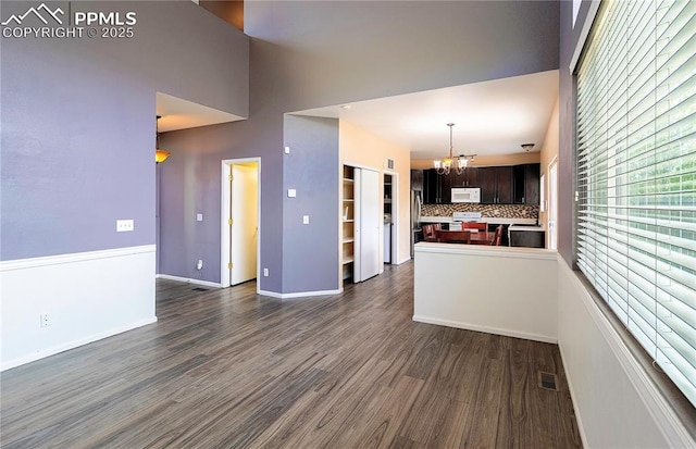 3808 Happy Jack Dr, Colorado Springs, CO 80922 - unfurnished living room featuring a chandelier, dark wood-type flooring, a high ceiling, and baseboards