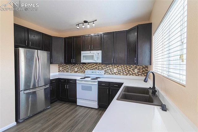 3808 Happy Jack Dr, Colorado Springs, CO 80922 - kitchen featuring white appliances, a sink, dark wood-style flooring, decorative backsplash, and light countertops