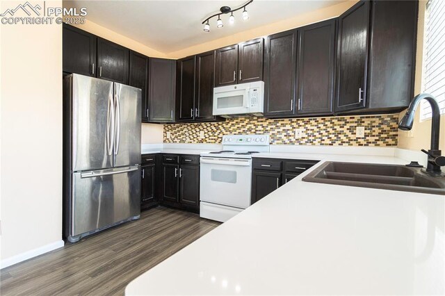 3808 Happy Jack Dr, Colorado Springs, CO 80922 - kitchen featuring white appliances, a sink, dark wood finished floors, light countertops, and decorative backsplash