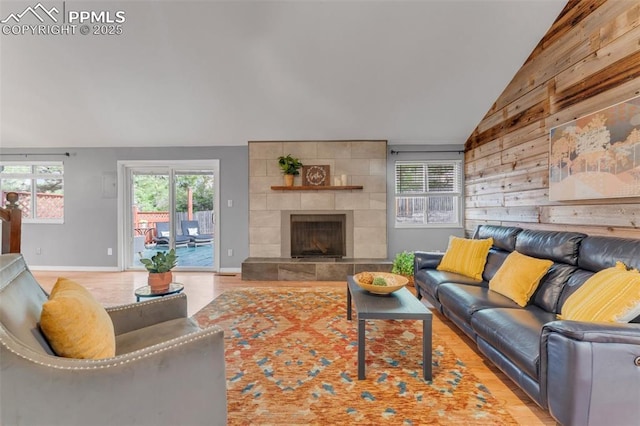 445 Wintery Cir, Colorado Springs, CO 80919 - living room featuring vaulted ceiling, wood walls, wood finished floors, a fireplace, and baseboards