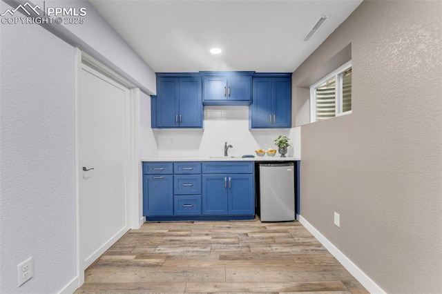 445 Wintery Cir, Colorado Springs, CO 80919 - kitchen featuring dishwasher, a sink, blue cabinetry, light wood finished floors, and light countertops