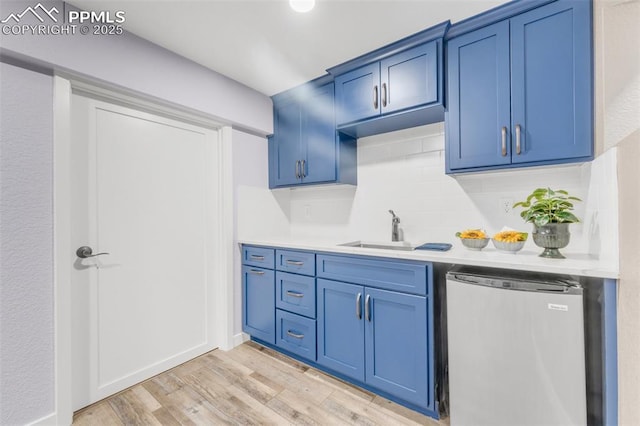 445 Wintery Cir, Colorado Springs, CO 80919 - kitchen featuring a sink, blue cabinetry, fridge, light wood-type flooring, and backsplash