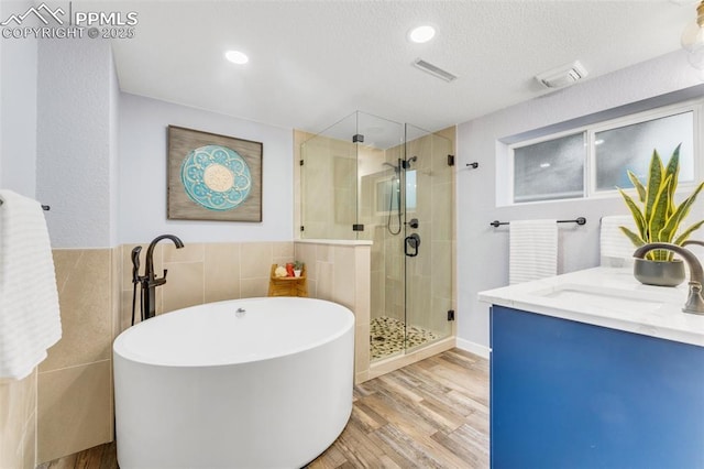 445 Wintery Cir, Colorado Springs, CO 80919 - bathroom with a stall shower, tile walls, a soaking tub, wood finished floors, and vanity