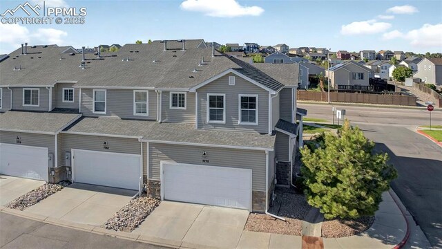 7470 Sandy Springs Pt, Fountain, CO 80817 - view of front of house featuring a residential view, an attached garage, driveway, a shingled roof, and stone siding