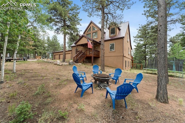 921 Cottonwood Lake Dr, Divide, CO 80814 - rear view of property featuring a trampoline, a fire pit, stairs, stucco siding, and metal roof