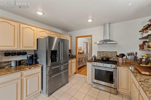 921 Cottonwood Lake Dr, Divide, CO 80814 - kitchen featuring appliances with stainless steel finishes, wall chimney range hood, light tile patterned floors, cream cabinets, and stone countertops