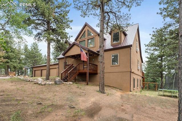 921 Cottonwood Lake Dr, Divide, CO 80814 - rear view of property with a trampoline, stucco siding, metal roof, a garage, and stairway