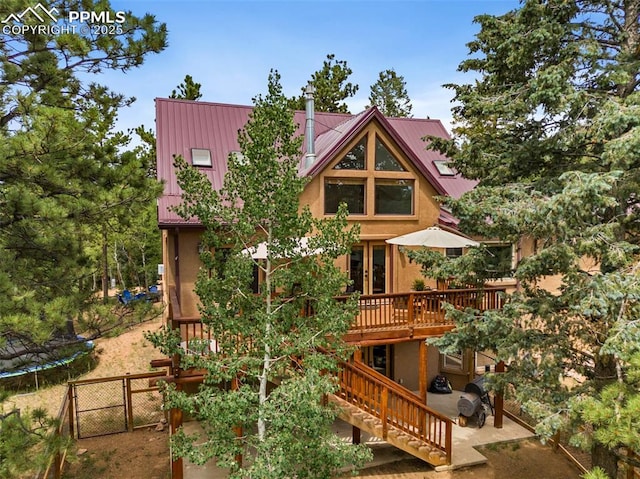 921 Cottonwood Lake Dr, Divide, CO 80814 - back of house featuring a trampoline, a deck, stairs, stucco siding, and metal roof