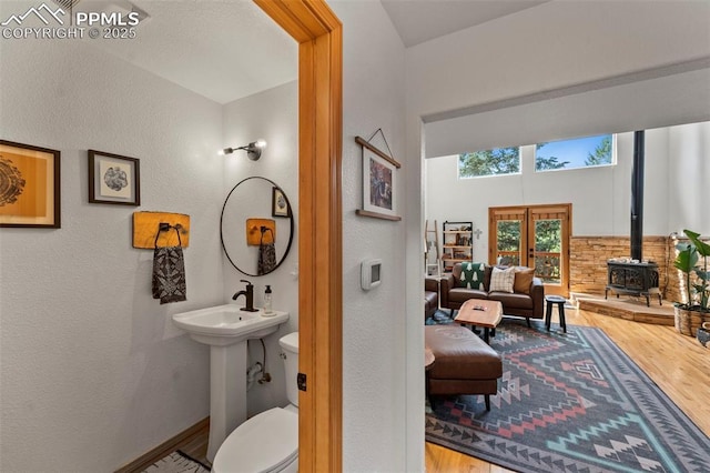 921 Cottonwood Lake Dr, Divide, CO 80814 - half bath featuring wood finished floors, a wood stove, a textured wall, french doors, and toilet