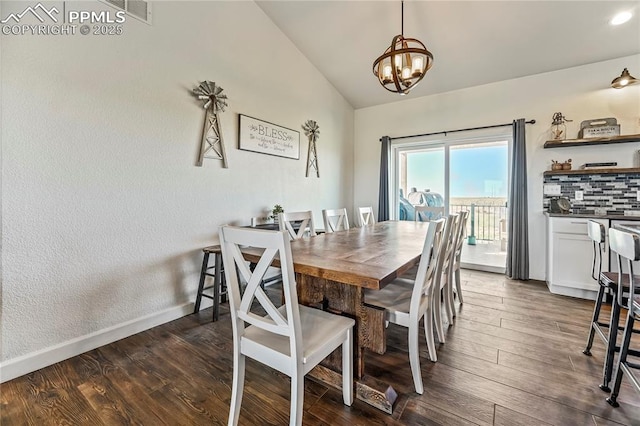 dining area with lofted ceiling, a chandelier, dark wood-style flooring, and baseboards