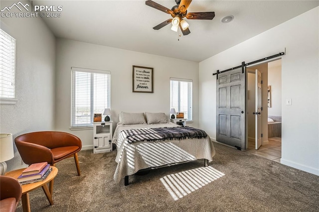 carpeted bedroom featuring a barn door, baseboards, ensuite bathroom, and ceiling fan