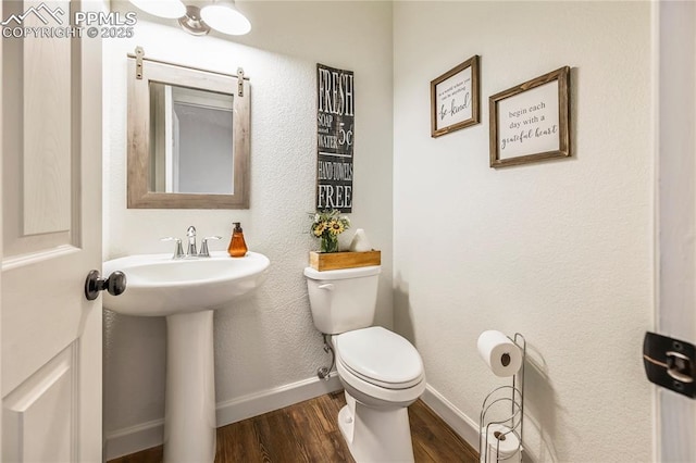 bathroom featuring wood finished floors, baseboards, and toilet