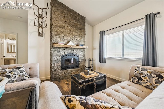 living area with a stone fireplace, lofted ceiling, baseboards, and wood finished floors