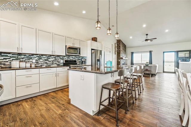 kitchen featuring stainless steel appliances, a breakfast bar, high vaulted ceiling, a center island, and backsplash