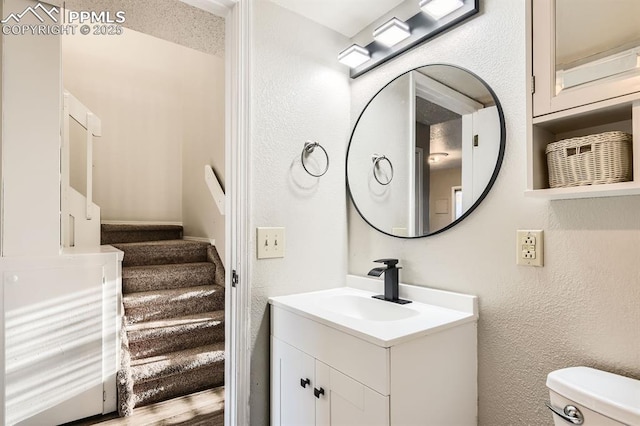 7911 Lexington Park Dr, Colorado Springs, CO 80920 - half bathroom featuring vanity, toilet, and a textured wall