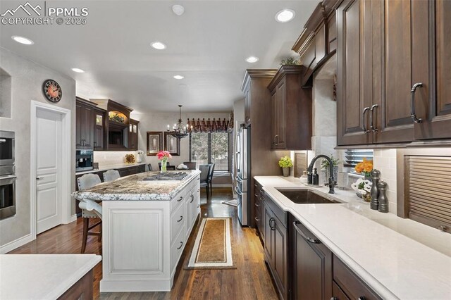 10061 Oak Knoll Ter, Colorado Springs, CO 80920 - kitchen featuring a sink, appliances with stainless steel finishes, a chandelier, a kitchen island, and dark brown cabinetry
