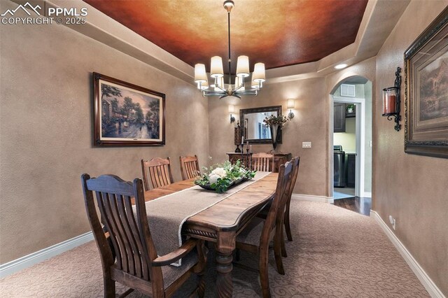 10061 Oak Knoll Ter, Colorado Springs, CO 80920 - dining area featuring carpet flooring, arched walkways, a chandelier, baseboards, and a tray ceiling